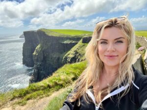 Woman taking a selfie on the cliffside path above the Cliffs of Moher in Ireland