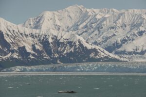 Hubbard Glacier below snow-covered mountains with floating ice in Alaska